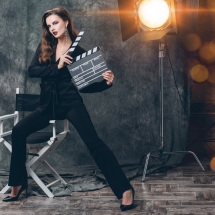 young beautiful stylish sexy woman on cinema backstage, holding movie clapper